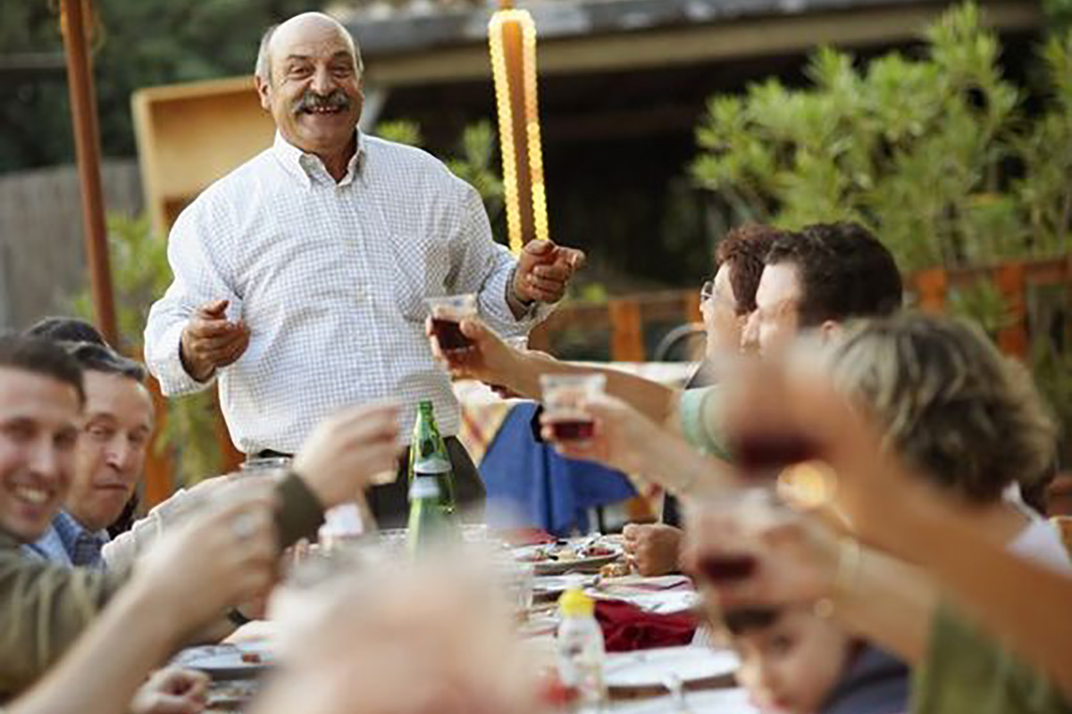 A group of people cheering each other around a table outside