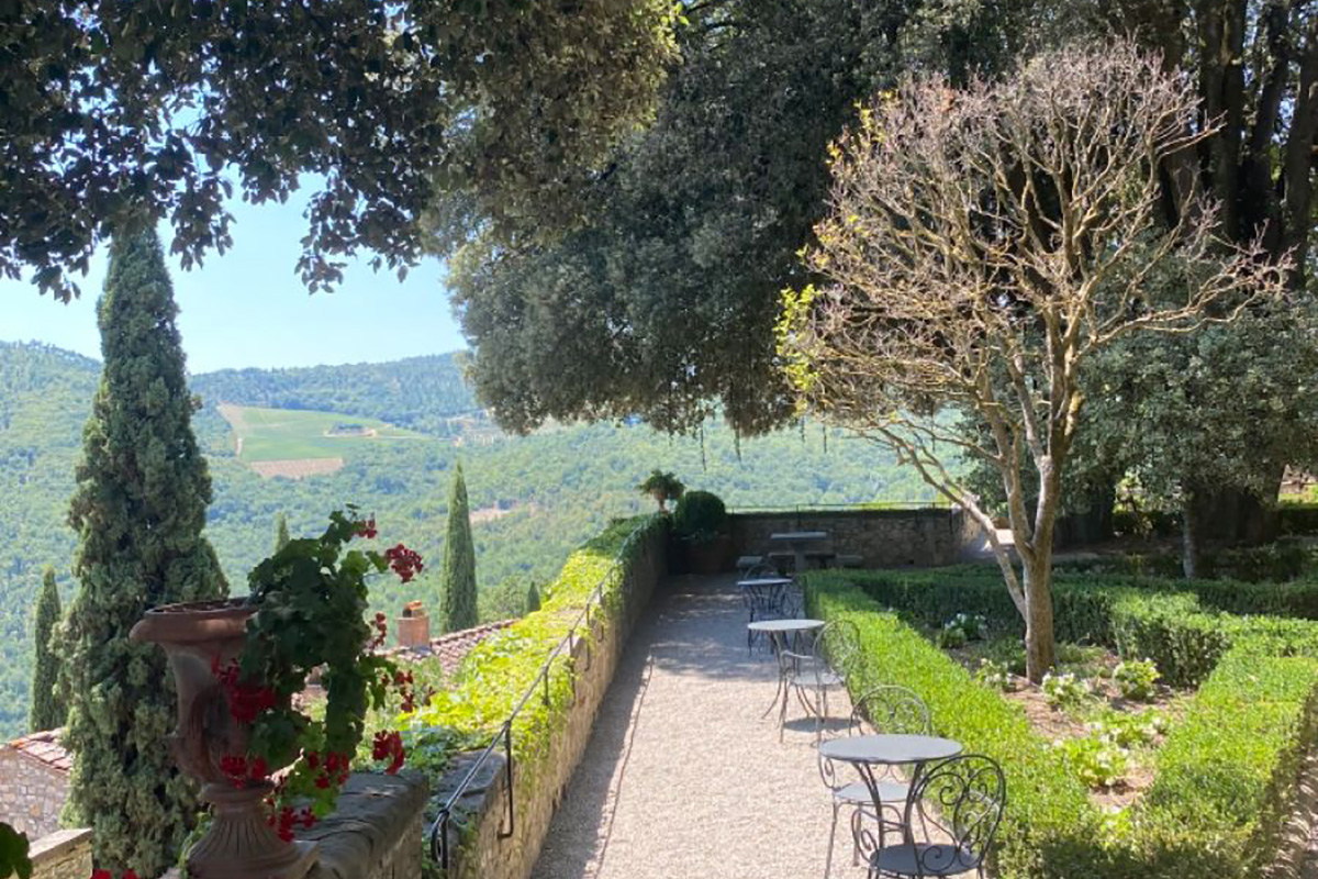 Cafe tables lining an Italian garden with hills in the background