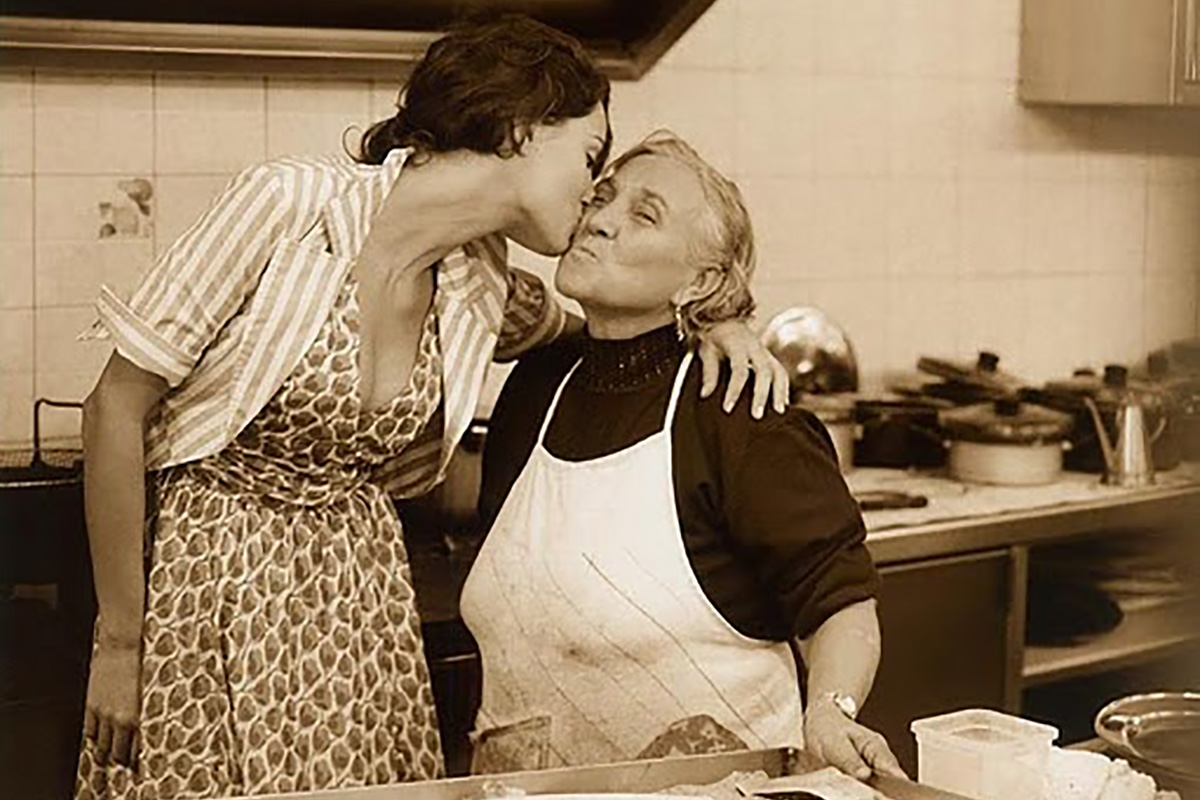 A sepia-toned photo of a woman kissing her grandmother