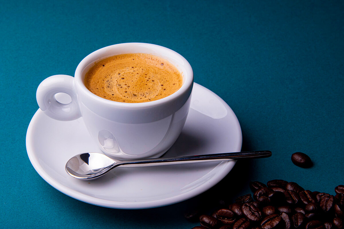 A full mug of coffee and a spoon sit on a saucer