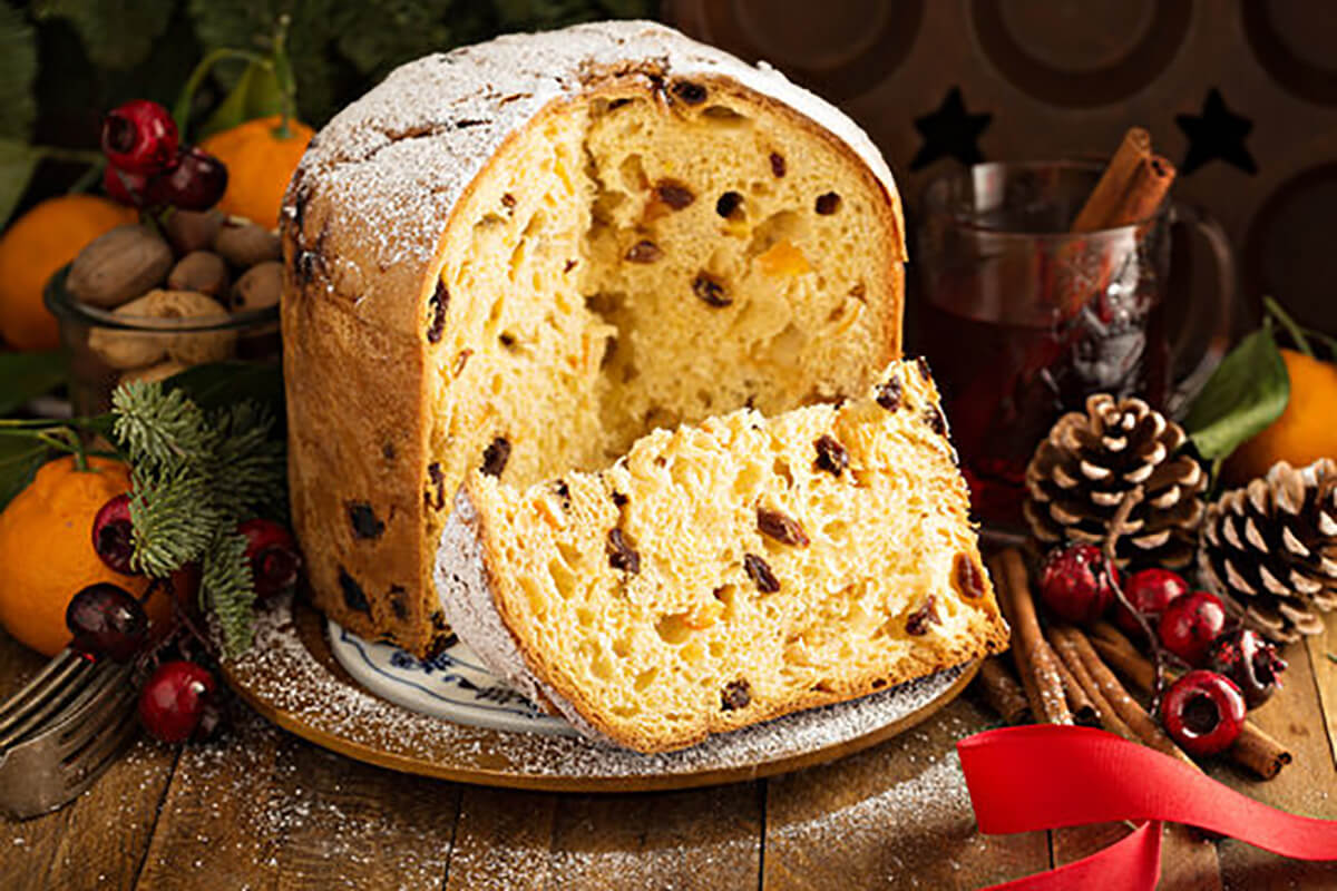 A loaf of panettone sits on a table, with a slice missing