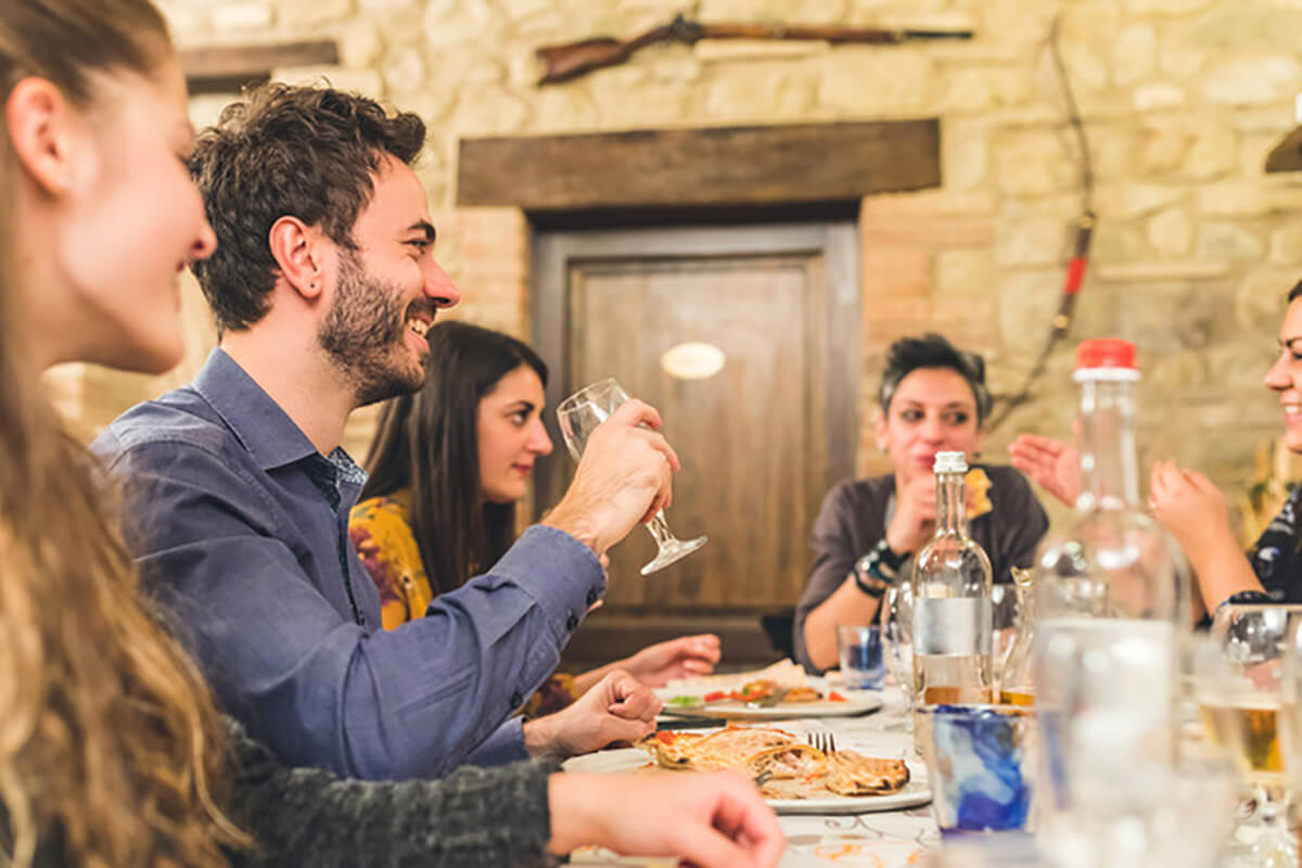 A group of people enjoying a meal and conversation around a dinner table in a rustic setting